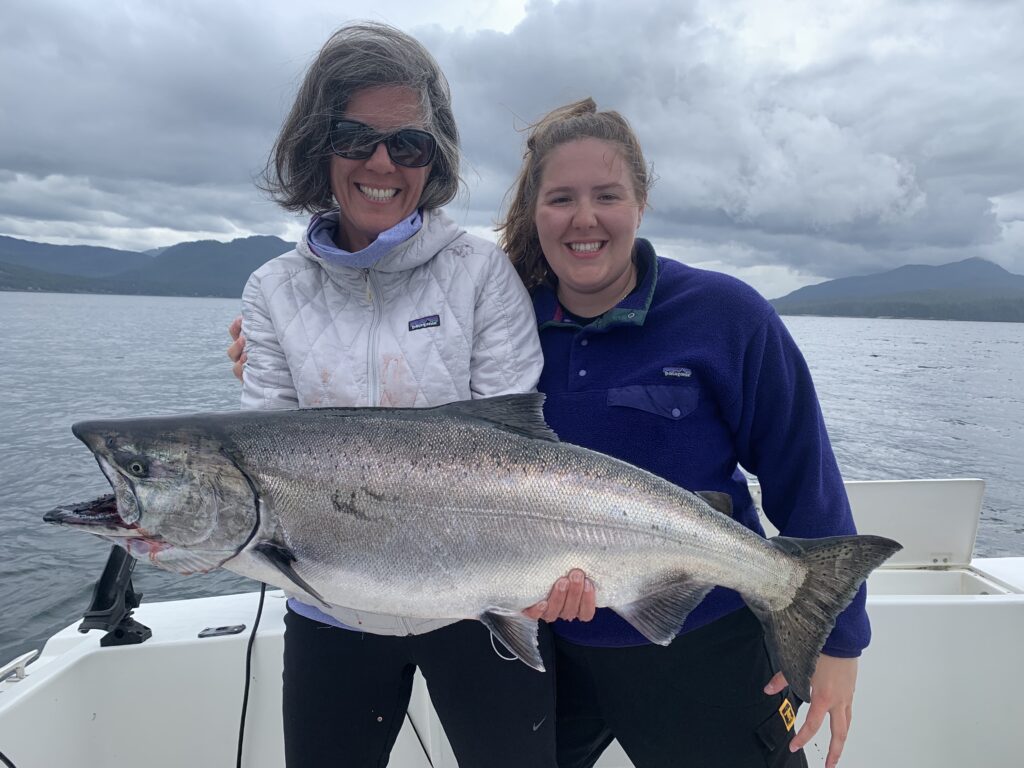 Sarah and Emma Campbell holding an ocean bright King salmon aboard the 4 C's during a Ketchikan fishing trip