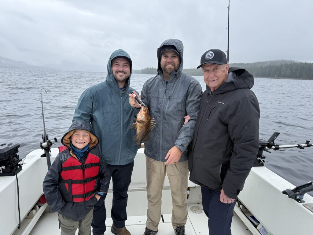 Ketchikan fishing report May photo showing four fishermen holding their first rockfish on the back deck of the 4 C's charter boat on a rainy day.