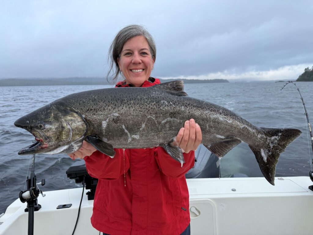 Sarah Campbell holding up a king salmon with slightly darker coloration while out on the water near Mountain Point.